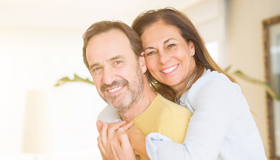 middle aged couple with dentures, showing off their smiles
