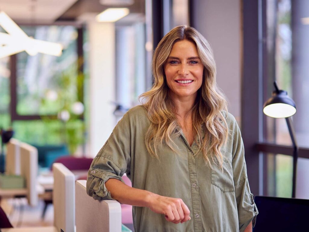 Woman smiling standing next to desk min