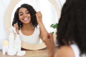 Happy woman flossing her teeth in the mirror to try and negate unhealthy oral habits.