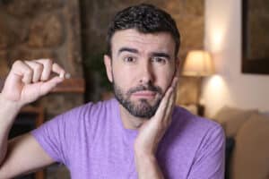 Man holding his jaw with one hand and a chipped piece of his tooth with his other hand in need of BioClear to repair it.
